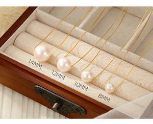 Detail showing 8mm to 14mm pink shell pearl sizes on gold necklaces in a wooden box