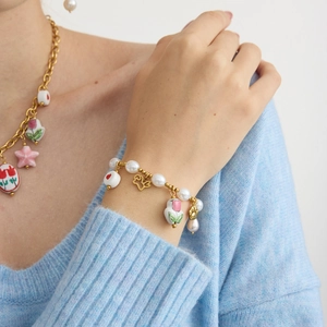 Detailed shot of pearl bracelet with red heart and tulip charms on female model