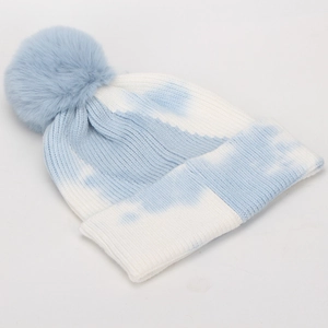 Detail of blue and white tie-dye ribbed knit hat with a large faux fur pom-pom ball