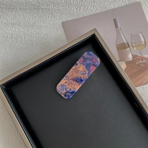 Detailed shot of a rectangular hair clip with blue marble pattern on a leather tray
