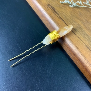 Detailed view of handmade gold hair pin with raw yellow crystal wrapped in wire