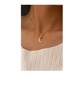 Detail of gold crescent moon pendant necklace with blue gemstone on a female model