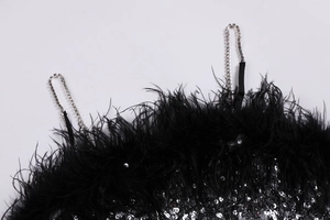 Détail de la robe noire à paillettes avec bordure en plumes et fines bretelles en strass