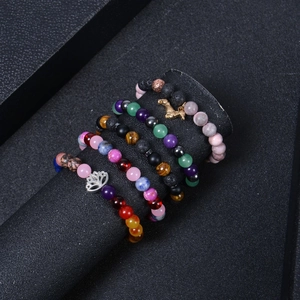 Detail view of 8mm natural stone yoga bracelets with lotus charm on black jewelry display