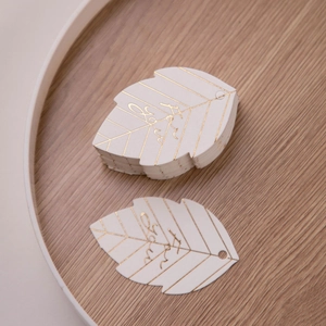 Detail of leaf-shaped white gift tags with gold foil veins and For You lettering
