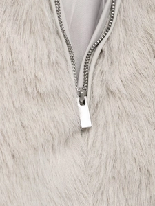 Detailed close-up of a silver metal zipper on a light gray faux fur fashion jacket