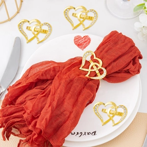 Close-up of four gold interlocking heart napkin rings with diamonds on a red napkin