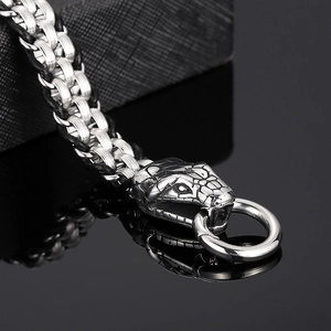 Braided stainless steel snake head bracelet with ring clasp on black reflective surface