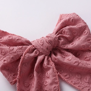 Close-up of pink cotton fabric hair bow with intricate floral embroidery details