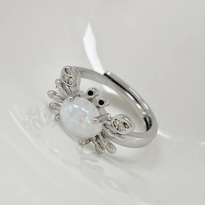 Anillo de cangrejo plateado con piedra lunar y cristales sobre un fondo blanco