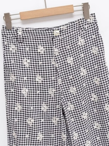 Détail d'un pantalon vichy noir et blanc avec de délicates broderies de fleurs blanches