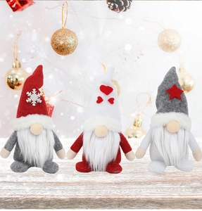 Close-up of three festive Christmas gnomes in red, white and grey on wooden surface