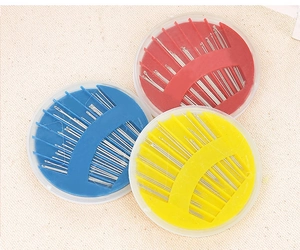 Three colorful round sewing needle cases with various steel needles for home repairs
