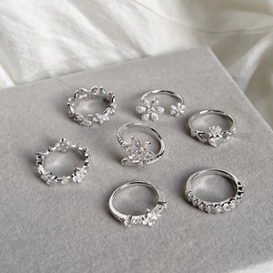 Detailed macro view of 7 pieces silver floral and heart rings on grey velvet jewelry stand