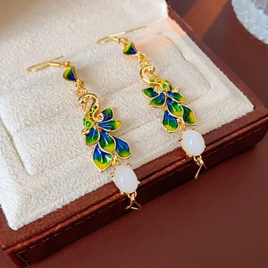 Dettaglio di orecchini a pavone placcati oro 14K con smalto e perla ovale bianca
