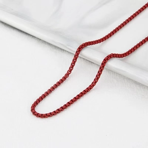 Detailed macro view of vibrant red box chain necklace with a smooth lacquered metal finish