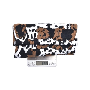 Folded cow pattern knit beanie for winter showing total weight of 88.5g on a digital scale