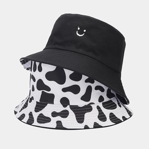 Detail of reversible fisherman hat with cow print and black smiley face embroidery