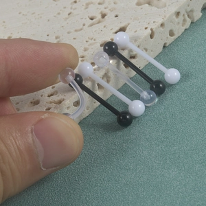 Close-up of flexible acrylic tongue rings in black, white and clear colors