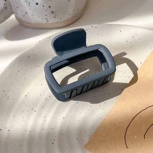 Detail of dark grey square hair claw clip with matte finish on decorative ceramic plate