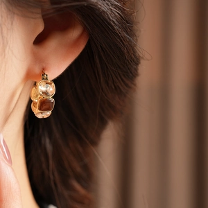 Close-up of vintage gold hoop earrings with square amber crystals on model ear