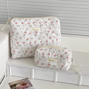 Macro detail of two quilted makeup bags with rose and green bow floral patterns