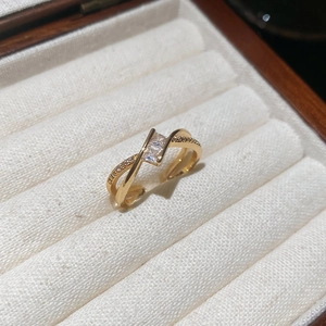Detail of adjustable gold ring with crisscross design and sparkling zircon stones