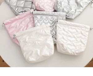 Close-up of heart-quilted drawstring storage bags in pink, silver, and white satin fabrics