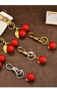 Detailed view of red cherry resin pendants with gold and silver metal lobster clasps