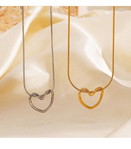 Detail of minimalist gold and silver hollow heart necklaces on silk background