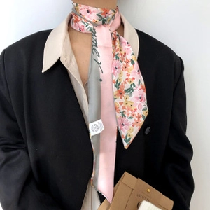 Foulard en soie rose à fleurs noué sur un col de chemise sous un blazer noir chic