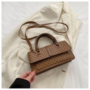 Close-up of brown litchi grain handbag with vintage patterns and rounded handle