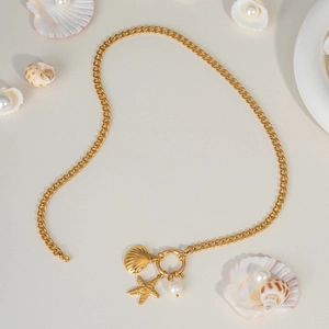 Detailed view of gold ocean charms with starfish, shell, and pearl on a cuban chain
