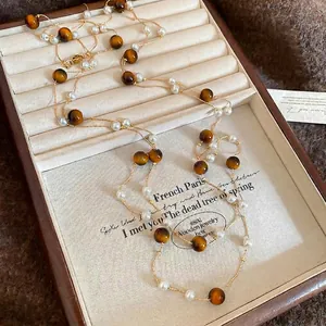 Elegante Tigerauge- und Perlenkette auf einem Vintage-Schmucktablett aus Holz