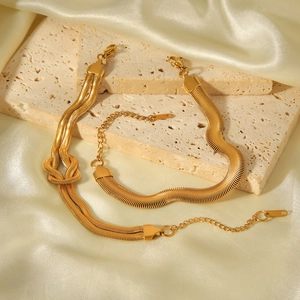 Detail view of 18k gold snake bone chain bracelet set on stone and satin background