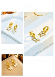 Macro view of gold hoop earrings with white shell butterfly charms on marble