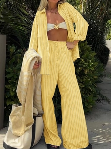 Women's yellow and white striped shirt and wide-leg pants set in a tropical resort setting
