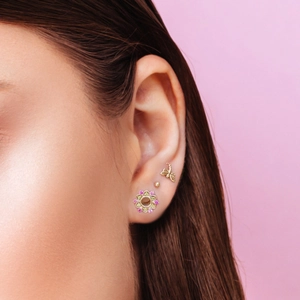 Close-up of 925 sterling silver dragonfly and floral studs on female ear cartilage