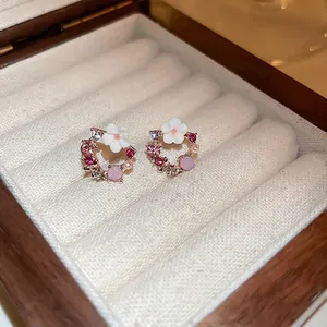 Eleganti orecchini a fiori in oro rosa con cristalli rosa e perle in una scatola portagioie