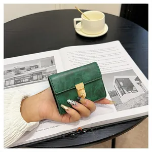 Close-up of dark green oil wax leather wallet featuring a gold metal buckle and neat stitching