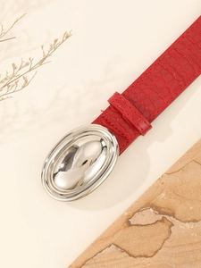 Close-up of red crocodile embossed leather belt with silver oval buckle and details