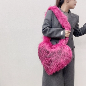 Macro detail of the plush heart-shaped crossbody bag in vibrant rose pink faux fur