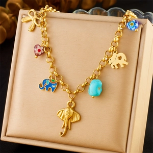 Gold elephant charm bracelet with blue enamel accents and heart pendants on a display box