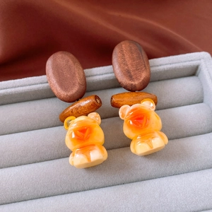 Detail of wooden bear earrings with resin pendant on grey velvet display case