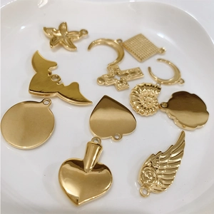 Golden titanium steel assorted pendants with butterfly, moon, and cross on white plate