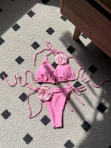 Detail of pink two-piece bikini featuring 3D fabric rose decorations and side-tie strings