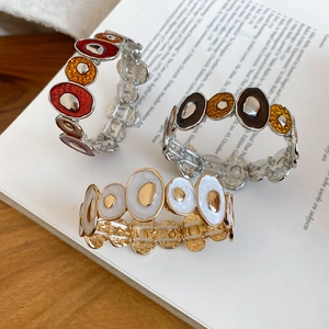 Close-up of enamel geometric bangles in red and gold on vintage book background
