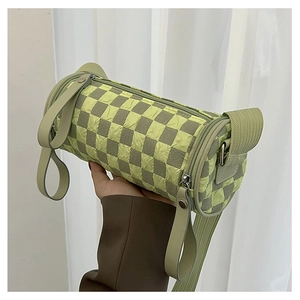 Close-up of pleated texture and green checkerboard pattern on the cylinder bag