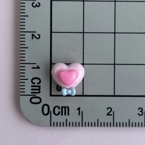 Close-up of pink heart resin craft piece with blue bow detail on a measurement grid