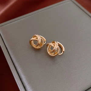 Close-up of gold layered knot earrings displayed on a luxury silk and jewelry box